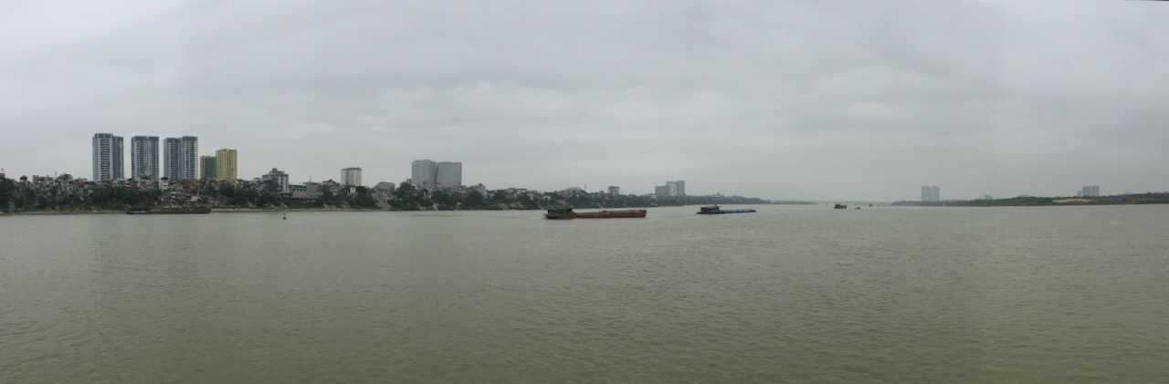 Skyline of Hanoi with freighters on the Red River in the foreground
